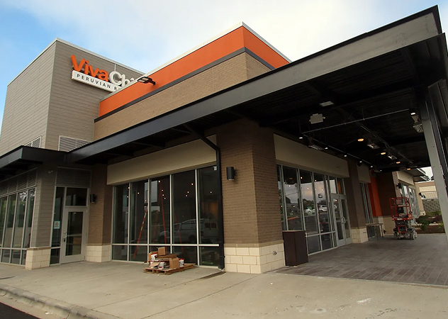 A modern commercial building with large glass windows and an overhanging roof. The sign reads 