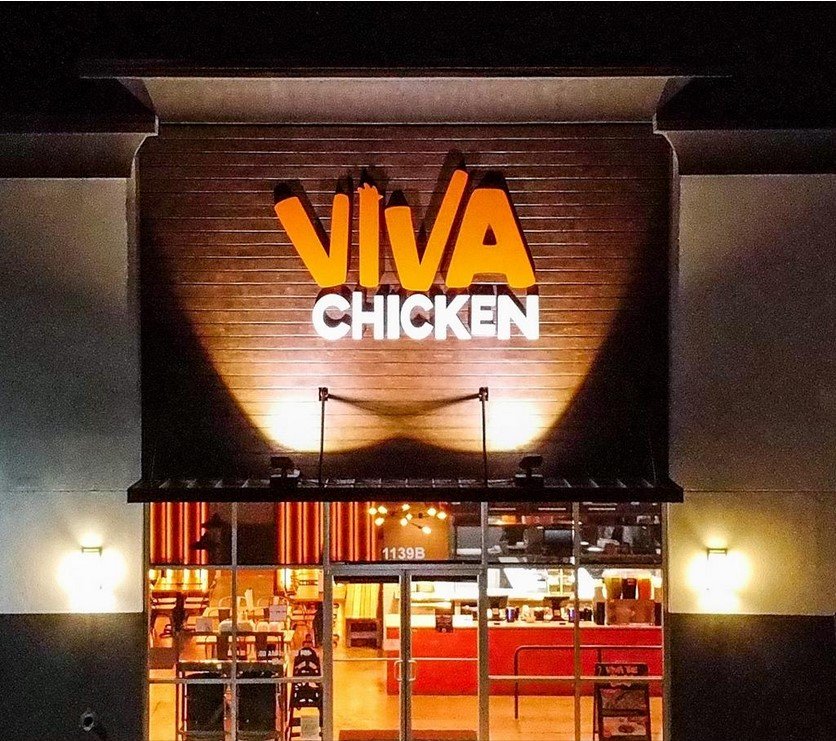 The front of a Viva Chicken restaurant at night, with a large illuminated 