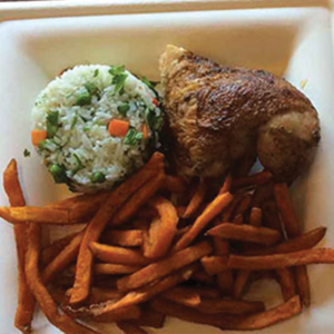 A plate with a serving of sweet potato fries, a portion of seasoned roasted chicken, and a round scoop of rice mixed with vegetables.